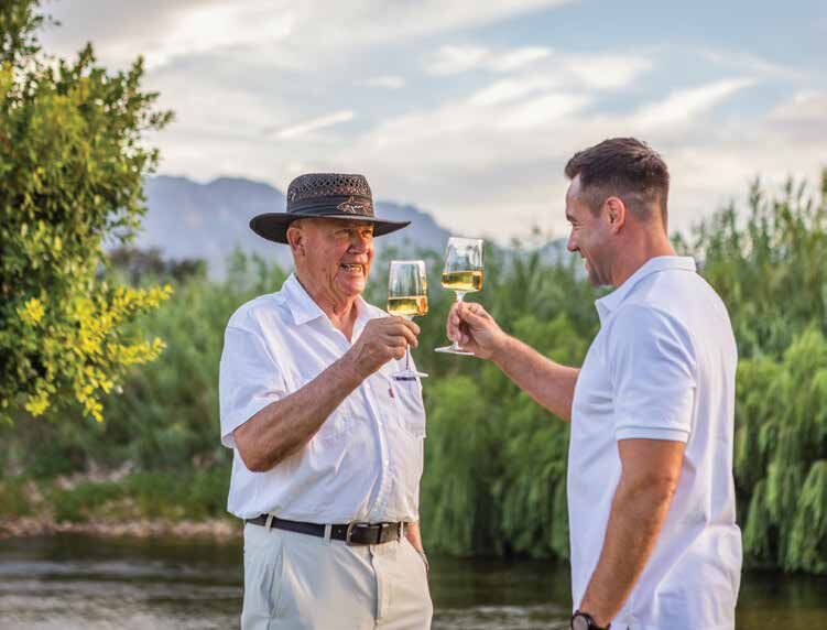 Two friends raising a glass of wine by the river